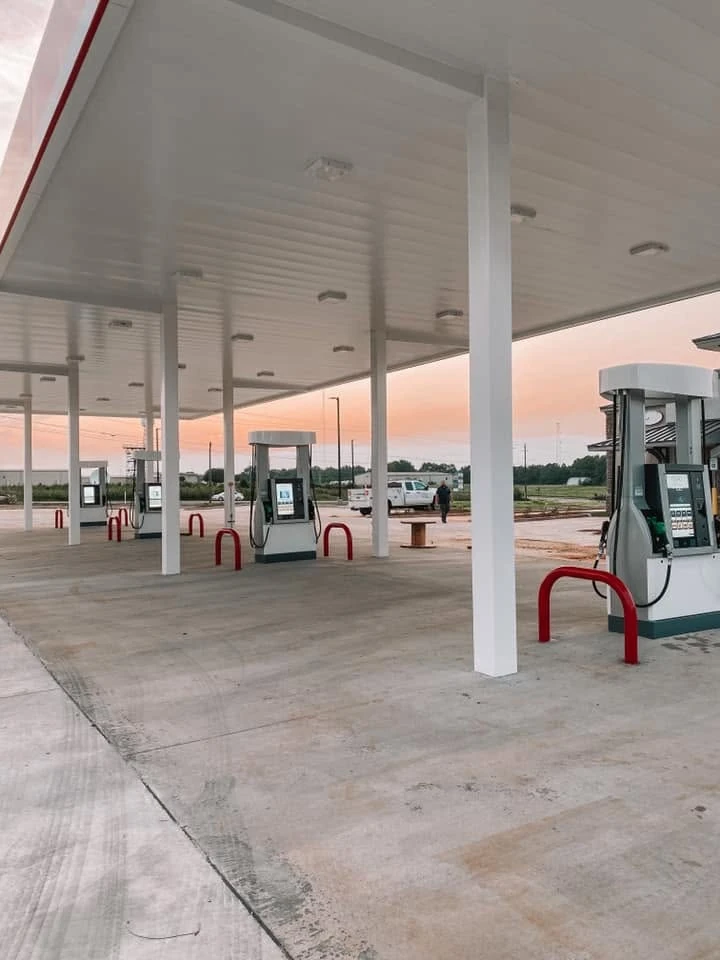 Fuel dispensers beneath a gas station canopy at sunset